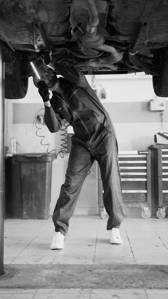 A mechanic inspecting a vehicle in a workshop, highlighting automotive maintenance.